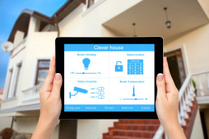 Female hands hold a tablet computer with system clever house on a screen on the background of the house